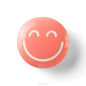 Coral-colored object with a smiley face design on a white background